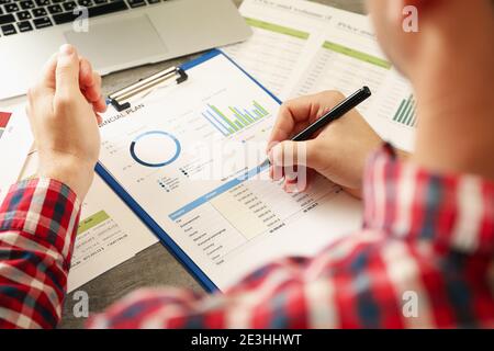 Junger Mann in rotem Hemd ist in der Finanzplanung beschäftigt Stockfoto