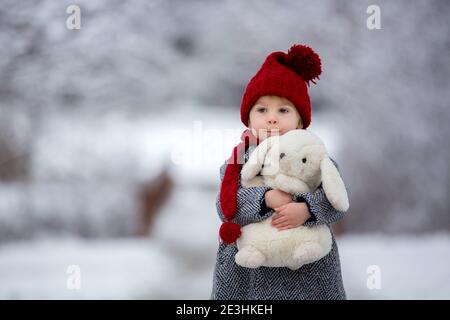 Schöne Kleinkind Kind, niedlichen Jungen, spielen in verschneiten Park Winterzeit, bewölkten Tag Stockfoto