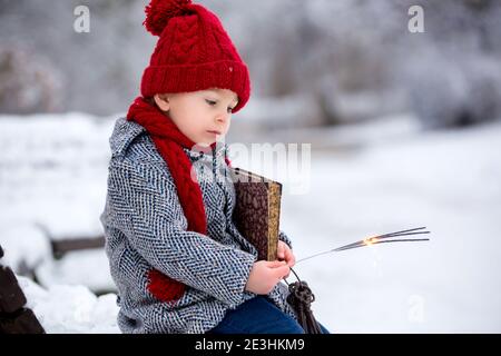 Schöne Kleinkind Kind, niedlichen Jungen, spielen in verschneiten Park Winterzeit, bewölkten Tag Stockfoto