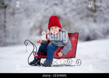 Schöne Kleinkind Kind, niedlichen Jungen, spielen in verschneiten Park Winterzeit, bewölkten Tag Stockfoto