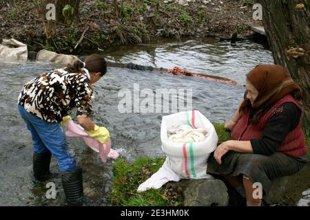 Kind und Großmutter in Rumänien auf dem Land waschen Wäsche in einem bach Stockfoto