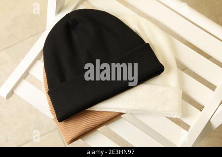 Drei stilvolle Beanies auf Holzstuhl, Draufsicht Stockfoto