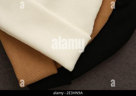 Drei stilvolle Beanies auf Stoffhintergrund, Nahaufnahme Stockfoto