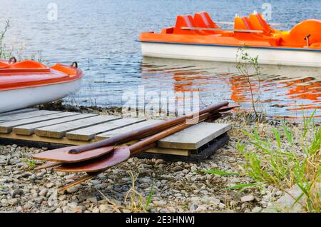 Am Ufer liegen hölzerne Ruder. Vergnügen Katamarane oder Boote auf See, die am Pier festgemacht sind. Tourismus im Nationalpark Urlaub. Aktiver Sommerurlaub. Stockfoto