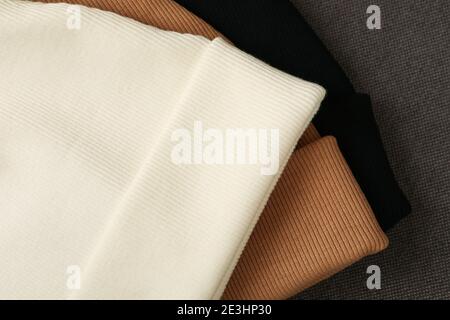 Drei stilvolle Beanies auf Stoffhintergrund, Nahaufnahme Stockfoto