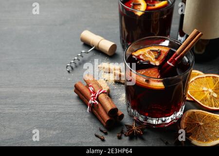 Flasche Wein und Tassen mit Glühwein mit Gewürzen auf Holz, ein rustikales Glühwein-Set mit Zutaten Stockfoto