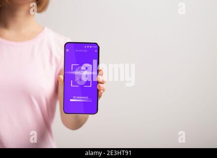 Lady Zeigt Telefon Mit Fingerabdruckscanner Auf Grauem Hintergrund, Abgeschnitten Stockfoto