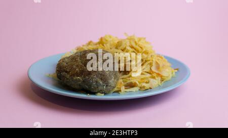 Geschmorter Weißkohl mit einem Cutlet Steak auf einem Teller. Ein Gericht der russischen Küche. In der UdSSR garnieren. Stockfoto