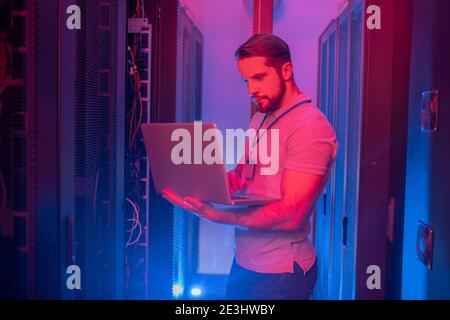 Mann, der im Serverraum auf einem Laptop arbeitet Stockfoto