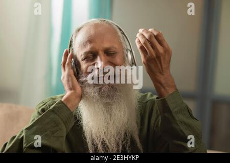 EIN GLÜCKLICHER BÄRTIGER MANN, DER MITSINGT, WÄHREND ER MUSIK HÖRT Stockfoto