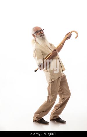 EIN BÄRTIGER ALTER MANN SPIELT GLÜCKLICH MIT SPAZIERSTOCK Stockfoto