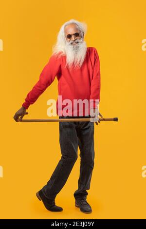 EIN FRÖHLICHER ALTER MANN POSIERT GLÜCKLICH MIT SPAZIERSTOCK Stockfoto