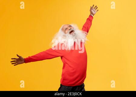 EIN FRÖHLICHER ALTER MANN, DER GLÜCKLICH DIE ARME HEBT UND NACH OBEN SCHAUT Stockfoto