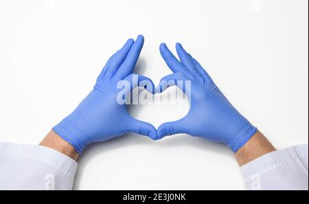 Zwei männliche Hände in blauem Latex sterile medizinische Handschuhe zeigen eine Geste des Herzens auf weißem Hintergrund, Konzept von Güte, Hilfe und Freiwilligenarbeit Stockfoto