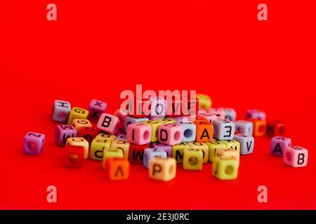 Bunte Holzwürfelperlen mit Buchstaben auf rotem festlichem Hintergrund, Wort "Liebe". Valentinstag. 14 Februar. Flach liegend, Draufsicht. Stockfoto