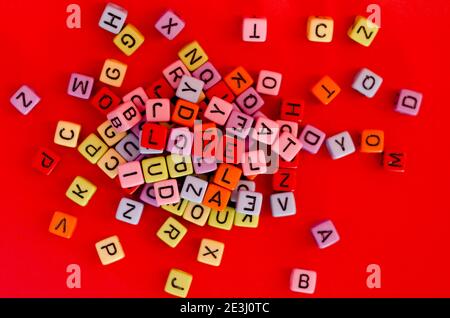 Bunte Holzwürfelperlen mit Buchstaben auf rotem festlichem Hintergrund, Wort "Liebe". Valentinstag. 14 Februar. Flach liegend, Draufsicht. Stockfoto