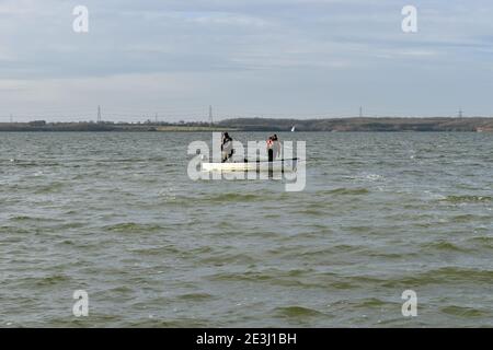 Zwei Männer fliegen Fischen von einem kleinen Boot auf Anglian Water Grapham Reservoir im Dezember. Stockfoto