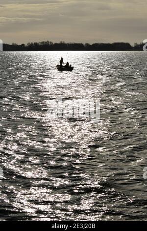 Zwei Männer fliegen Fischen von einem kleinen Boot auf Anglian Water Grapham Reservoir im Dezember. Stockfoto