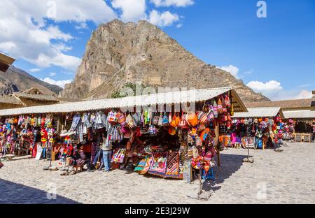 Bunte lokale Touristen Souvenirstände in Ollantaytambo und Blick auf Pinkuylluna im Heiligen Tal in Urubamba, Cusco Region, Südperu Stockfoto