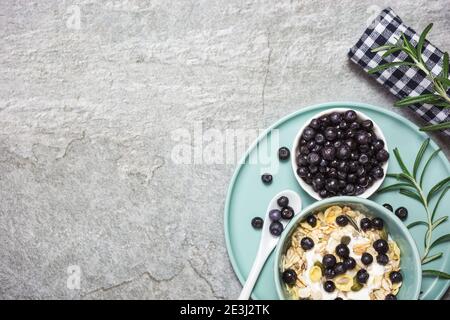 Griechisches Joghurt-Müsli mit frischen Heidelbeeren auf einem Steintisch, Draufsicht mit Platz für Text. Gesunde Lebensmittel, Snack oder Frühstück. Stockfoto