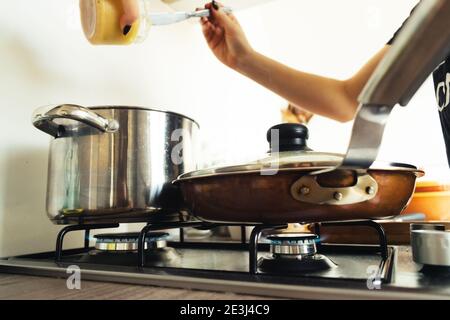 Frauen, die in der Küche arbeiten und Souce im Kessel hinzufügen. Stockfoto