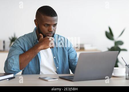 Fokussierter Afroamerikanischer Geschäftsmann, Der Mit Laptop Im Büro Arbeitet Stockfoto