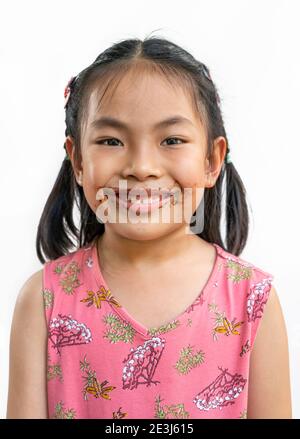 Portrait Asian niedlich Kind Mädchen mit chaotisch von Schokolade um den Mund, großes Lächeln auf niedlichen Gesicht, schwarze Haare, das Tragen schöner rosa Kleid, isoliert im Stockfoto