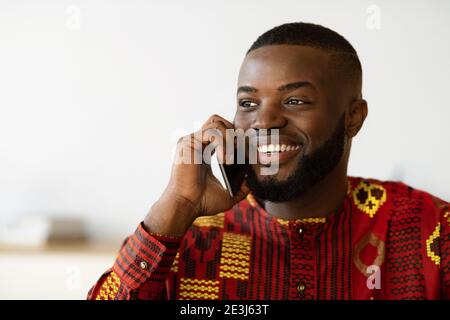 Mobile Anrufe. Lächelnder Afrikanischer Amerikanischer Kerl Im Ethnischen Hemd, Der Auf Dem Handy Spricht Stockfoto