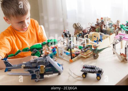 SAINT-PETERSBURG, RUSSLAND - NOVEMBER 26, 2020 Junge spielen mit lego-Steinen sitzen am Schreibtisch, Welt der Dinosaurier von Kind gebaut Stockfoto