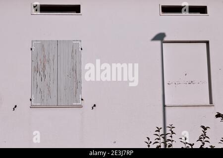 Zwei Fenster in einer weißen Wand mit ruinierten hölzernen Fensterläden (Pesaro, Italien, Europa) Stockfoto