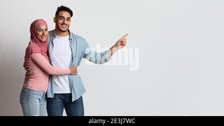 Glückliches Muslimisches Paar Umarmt Und Zeigt Beiseite Auf Copy Space Stockfoto