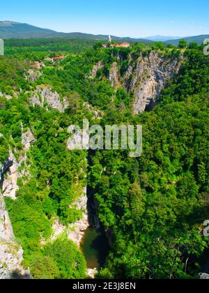 Blick auf die tiefe Schlucht des Flusses Reka und Dorf mit ländlichen Kirche, Skocjan Höhlen, Slowenien Stockfoto