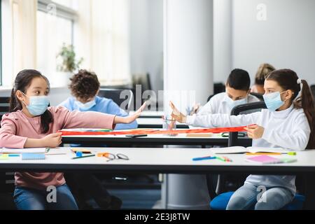 Verschiedene Schüler tragen Gesichtsmasken, die Abstand auf Armlänge halten Stockfoto