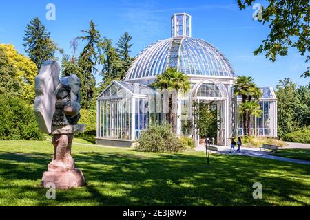 Das gemäßigte Gewächshaus im Konservatorium und Botanischen Garten von Genf und die Skulptur 'Portatore di zucche'. Stockfoto