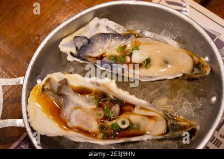 Oyster frisch in Sojasauce japanische Delikatesse serviert auf Eis Topping Gemüse in Café-Café und Restaurant in Udon Thani, Thailand Stockfoto