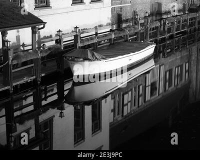 Boot Reflexion auf Wasserkanal bei Nacht in Brügge, Belgien. Schwarzweiß-Bild. Stockfoto