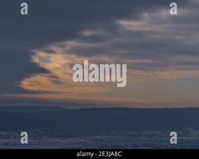 Schöne Luftpanoramablick auf die Ausläufer der Schwäbischen Alb, Deutschland im Winter mit Dorf, schneebedeckten Feldern und Silhouetten der Hohenzollern Burg. Stockfoto