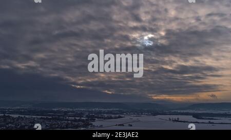 Atemberaubende Winterlandschaft der schneebedeckten Ausläufer der Schwäbischen Alb von Wurmlingen aus gesehen, mit der Silhouette der durchscheinenden Sonne. Stockfoto