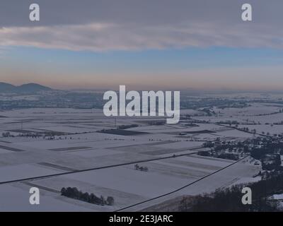 Schöne Luftaufnahme der Winterlandschaft mit Tal von schneebedeckten strukturierten landwirtschaftlichen Feldern, Landstraße und Stadt Rottenburg am Neckar, Deutschland. Stockfoto