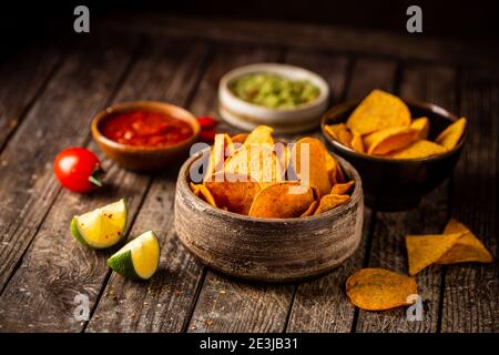 Zwei Biowls gelber Mais Tortilla Nachos Chips mit Salsa Und Guacamole Sauce auf Holzgrund Stockfoto