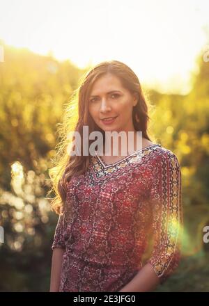 Porträt der jungen Frau in lässigen Sommerkleid, starke Sonnenuntergang Hintergrundbeleuchtung mit schönen Bokeh Stockfoto