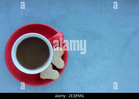 Rote Tasse Kaffee und herzförmige Kekse auf grauem Betongrund. Stockfoto
