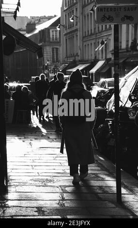 PARIS, FRANKREICH - 28. JANUAR 2017: Urbane Szene im alten Marais Viertel bei Sonnenuntergang. Leute, die auf dem schmalen Gehweg in die Schaufenster schauen; entspannen in Ca Stockfoto