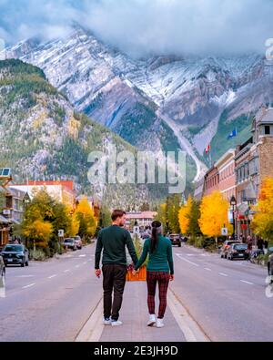 Ein Paar besucht die Stadt Banff Alberta Kanada, ein Paar Männer und Frauen, die auf der Straße von Banff mit riesigen felsigen Bergen im Hintergrund in Kanada spazieren gehen. Stockfoto