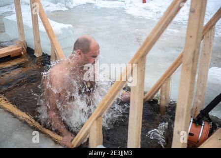 Der Mensch badet am Dreikönigstag im Fluss Newa, Sankt Petersburg, in kaltes Wasser des Eislochs. Traditionelles Eisschwimmen in der orthodoxen Kirche Heilige Epiphanie. Sai Stockfoto