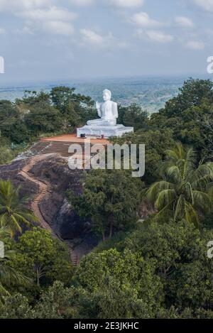 Blick auf die weiße Skulptur des sitzenden Buddha auf der Ambastala-Hochebene (Mango-Hochebene) an einem bewölkten Tag. Mihintale, Sri Lanka Stockfoto