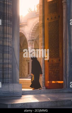 Istanbul, Türkei - 18 2017. September: Eine muslimische Frau besucht die Suelymaniye Moschee, während goldenes Abendlicht vom Hof ausstrahlt. Stockfoto