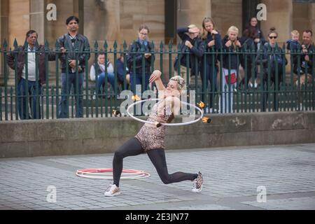 Edinburgh, Schottland - 6. August 2017: Eine weibliche Street-Perfomerin beim Edinburgh Fringe Festival führt einen gefährlichen Stunt mit Feuer und einem Hula Hoop Reifen auf. Stockfoto