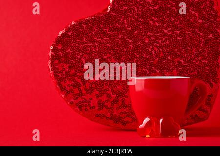 Rote Tasse Becher und zwei Schokoladenherzen und große Box dahinter auf scharlachrotem oder rotem Hintergrund. Flache Lay-Komposition. Valentinstag-Konzept. Draufsicht, Kopieren Stockfoto