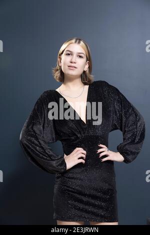 Ein 19-jähriges Mädchen mit gebleichten Strähnen und einer bob-Frisur in einem modischen schwarzen Glitzer-Cocktailkleid lächelt. Der dunkelblaue Hintergrund. Stu Stockfoto